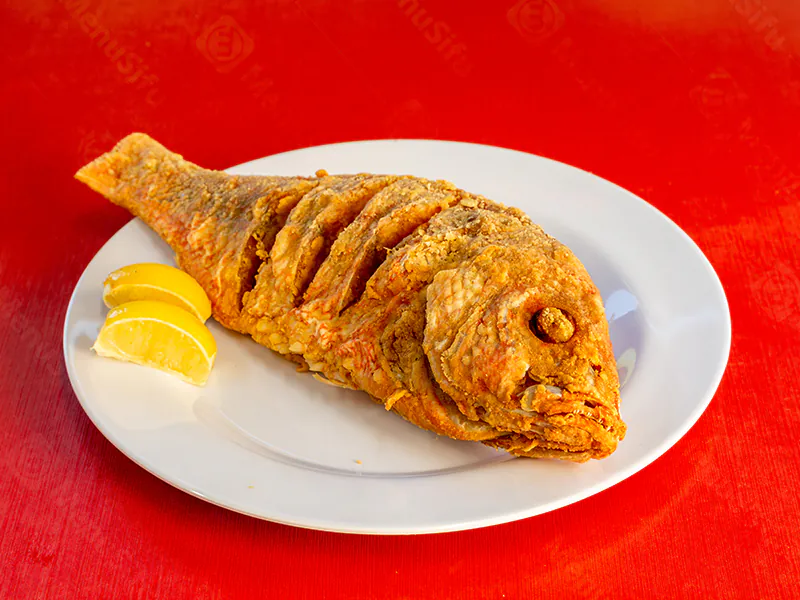 Crispy whole fried red snapper with fresh lemon wedges at This is Seafood, a Seafood Restaurant in District Heights